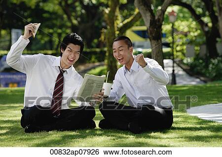 Two men get excited as they read the newspaper in the park View Large Photo Image Stock Photograph - Two men get excited as they read the newspaper in the park. Fotosearch