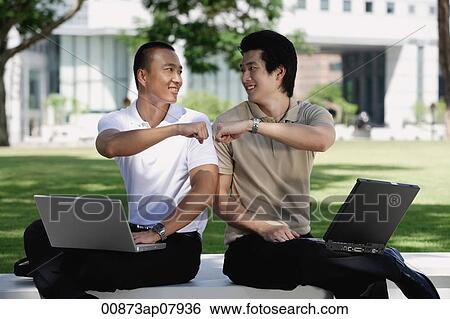 Stock Photograph - Two men use their laptops in the park. Fotosearch