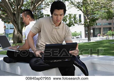 Two men use their laptops in the park View Large Photo Image Stock Photography - Two men use their laptops in the park. Fotosearch