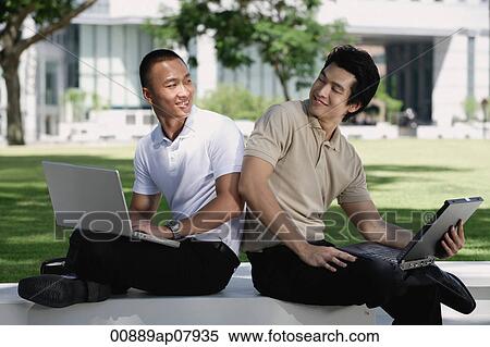 Two men use their laptops in the park View Large Photo Image Stock Photography - Two men use their laptops in the park. Fotosearch