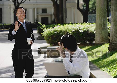 Two men wave at each other in the park View Large Photo Image Stock Image - Two men wave at each other in the park. Fotosearch