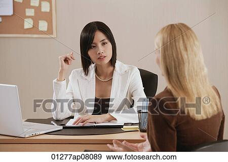 Two woman talk together at work View Large Photo Image Stock Photo - Two woman talk together at work. Fotosearch