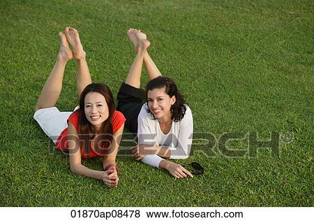 Two women relaxing in the park, looking at camera View Large Photo Image Stock Photo - Two women relaxing in the park, looking at camera. Fotosearch