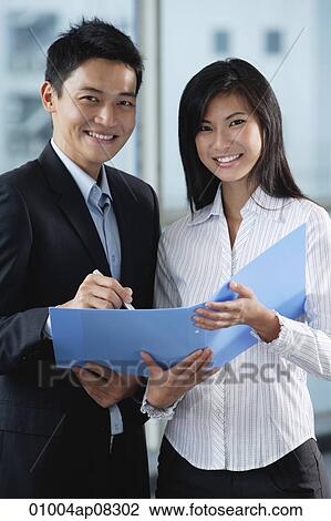 Two work colleagues smile at the camera together View Large Photo Image Stock Image - Two work colleagues smile at the camera together. Fotosearch