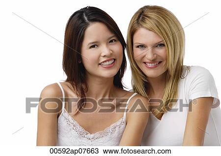 Two young woman wearing white shirts and smiling at camera View Large Photo Image Stock Image - Two young woman wearing white shirts and smiling at camera. Fotosearch