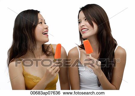 Two young women eating Popsicle, smiling View Large Photo Image Stock Photograph - Two young women eating Popsicle, smiling. Fotosearch