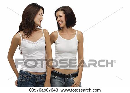Two young women standing together and looking at each other View Large Photo Image Stock Image - Two young women standing together and looking at each other. Fotosearch
