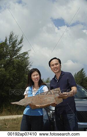 Woman and man standing by car, reading map, looking at camera View Large Photo Image Stock Image - Woman and man standing by car, reading map, looking at camera. Fotosearch