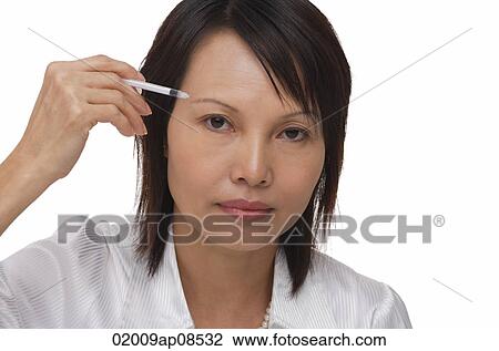 Woman applying make-up while looking at camera View Large Photo Image Stock Image - Woman applying make-up while looking at camera. Fotosearch