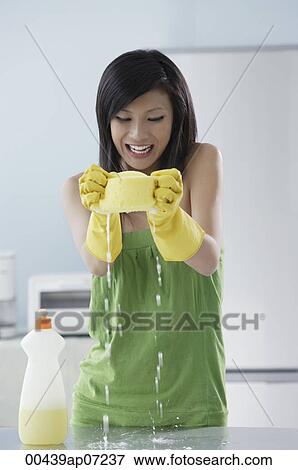 woman cleaning kitchen, squeezing water from sponge onto counter, smiling View Large Photo Image Stock Photo - woman cleaning kitchen, squeezing water from sponge onto counter, smiling. Fotosearch