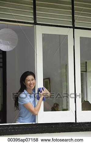 Woman cleaning windows at home, smiling at camera View Large Photo Image Stock Photo - Woman cleaning windows at home, smiling at camera. Fotosearch
