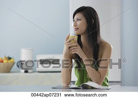 woman drinking out of mug in kitchen with magazine View Large Photo Image Stock Image - woman drinking out of mug in kitchen with magazine. Fotosearch