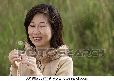 woman holding flower, standing in tall grass, outdoors View Large Photo Image Stock Photo - woman holding flower, standing in tall grass, outdoors. Fotosearch