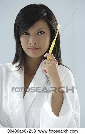 Stock Photo - woman holding toothbrush, looking at camera. Fotosearch