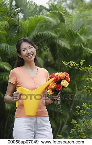 Woman in garden, holding bouquet of flowers and watering can View Large Photo Image Stock Photo - Woman in garden, holding bouquet of flowers and watering can. Fotosearch