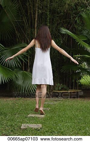 Woman in garden, walking on stepping stones, hands outstretched, rear view View Large Photo Image Stock Image - Woman in garden, walking on stepping stones, hands outstretched, rear view. Fotosearch
