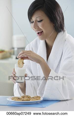 woman in kitchen, dipping cooking in glass of milk, smiling View Large Photo Image Stock Photo - woman in kitchen, dipping cooking in glass of milk, smiling. Fotosearch