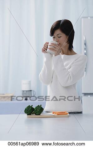 Woman in kitchen, drinking from a cup View Large Photo Image Stock Photo - Woman in kitchen, drinking from a cup. Fotosearch
