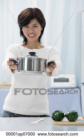 Woman in kitchen, holding crocking pot towards camera View Large Photo Image Stock Image - Woman in kitchen, holding crocking pot towards camera. Fotosearch