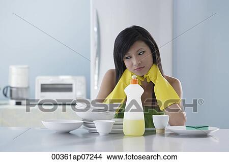 woman in kitchen, looking at pile of dishes, thinking View Large Photo Image Picture - woman in kitchen, looking at pile of dishes, thinking. Fotosearch