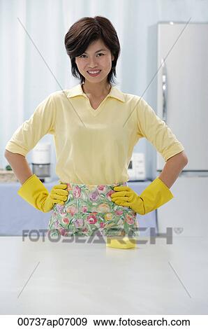 Woman in kitchen, wearing gloves and apron, hands on hips View Large Photo Image Stock Photo - Woman in kitchen, wearing gloves and apron, hands on hips. Fotosearch