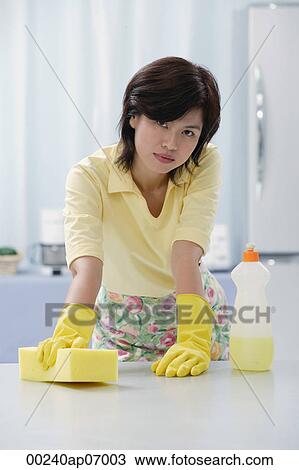 Woman in kitchen wearing gloves, cleaning kitchen counter with sponge View Large Photo Image Stock Image - Woman in kitchen wearing gloves, cleaning kitchen counter with sponge. Fotosearch