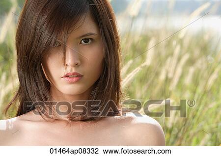 Stock Image - Woman in long grass looking at camera. Fotosearch