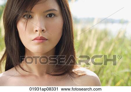 Stock Image - Woman in long grass looking at camera. Fotosearch