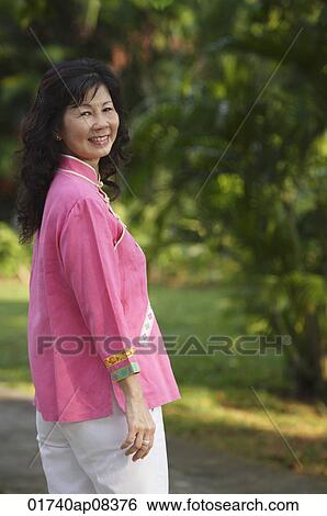 Woman in park, smiling at camera View Large Photo Image Stock Photograph - Woman in park, smiling at camera. Fotosearch