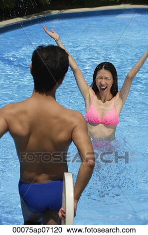 Woman in swimming pool, arms outstretched, looking at man standing in front of her View Large Photo Image Stock Image - Woman in swimming pool, arms outstretched, looking at man standing in front of her. Fotosearch