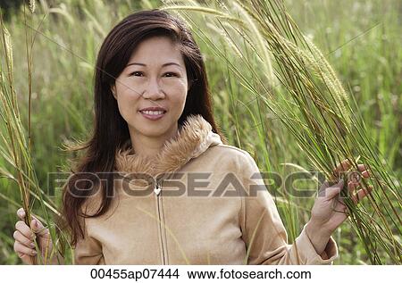 Woman in tall grass, nature, looking at camera, smiling View Large Photo Image Picture - Woman in tall grass, nature, looking at camera, smiling. Fotosearch