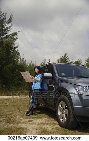 Woman leaning against SUV, reading map View Large Photo Image Stock Photo - Woman leaning against SUV, reading map. Fotosearch