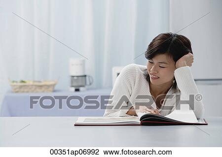 Woman leaning on table, reading a book View Large Photo Image Stock Image - Woman leaning on table, reading a book. Fotosearch