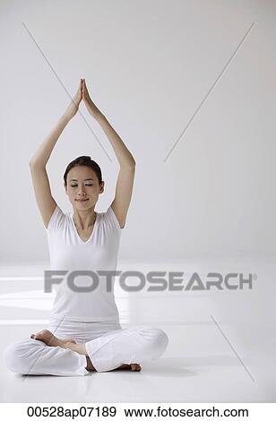 Woman sitting cross legged on floor in yoga posture, with arms raised over head in prayer View Large Photo Image Stock Photo - Woman sitting cross legged on floor in yoga posture, with arms raised over head in prayer. Fotosearch