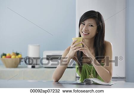 woman sitting in kitchen with magazine and mug, smiling at camera View Large Photo Image Stock Image - woman sitting in kitchen with magazine and mug, smiling at camera. Fotosearch