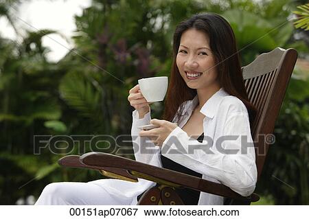 Woman sitting outdoors, having a cup of tea, smiling at camera View Large Photo Image Stock Photo - Woman sitting outdoors, having a cup of tea, smiling at camera. Fotosearch