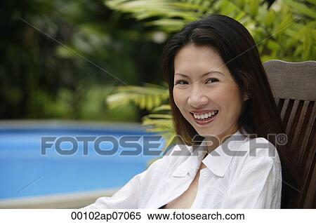 Stock Photography - Woman sitting outdoors, smiling at camera. Fotosearch