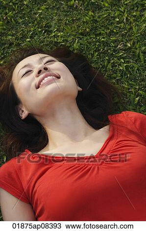 Woman smiling, lying on grass View Large Photo Image Stock Image - Woman smiling, lying on grass. Fotosearch