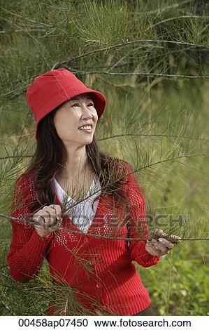 Woman standing by tree, outdoors, nature View Large Photo Image Stock Image - Woman standing by tree, outdoors, nature. Fotosearch