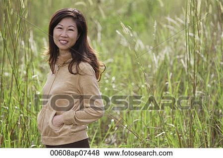 woman standing in tall grass, nature, smiling at camera View Large Photo Image Stock Photo - woman standing in tall grass, nature, smiling at camera. Fotosearch