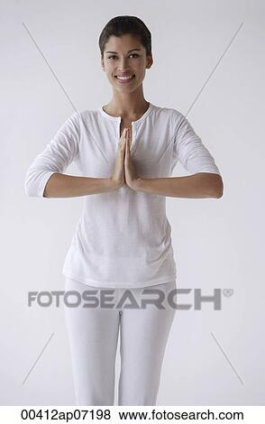 Woman standing with hands in namaste, prayer, smiling, looking at camera View Large Photo Image Stock Photo - Woman standing with hands in namaste, prayer, smiling, looking at camera. Fotosearch