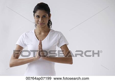Woman standing with hands in namaste, prayer, looking at camera View Large Photo Image Stock Photo - Woman standing with hands in namaste, prayer, looking at camera. Fotosearch