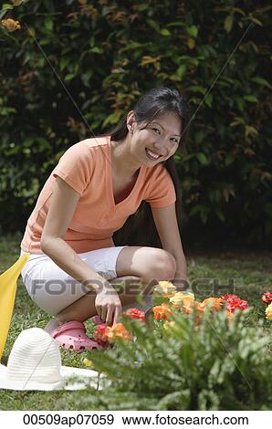 Woman tending to flower bed in garden View Large Photo Image Stock Photo - Woman tending to flower bed in garden. Fotosearch