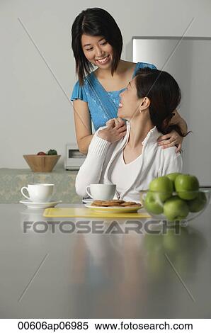 Woman turning to look at adult daughter standing behind her View Large Photo Image Stock Photography - Woman turning to look at adult daughter standing behind her. Fotosearch