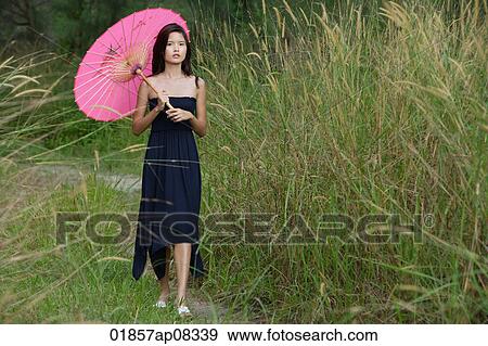 Woman walking in long grass with parasol View Large Photo Image Stock Photo - Woman walking in long grass with parasol. Fotosearch