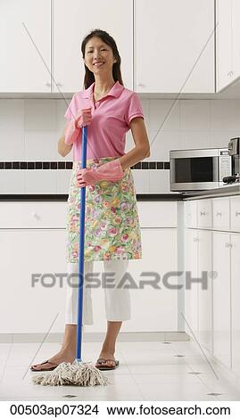 Woman with mop in kitchen, cleaning, looking at camera, smiling View Large Photo Image Picture - Woman with mop in kitchen, cleaning, looking at camera, smiling. Fotosearch