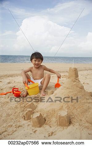 Young boy on beach building sand castle, smiling View Large Photo Image Stock Photograph - Young boy on beach building sand castle, smiling. Fotosearch