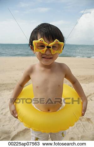 Young boy on beach wearing yellow star goggles and holding yellow float around waist View Large Photo Image Stock Image - Young boy on beach wearing yellow star goggles and holding yellow float around waist. Fotosearch