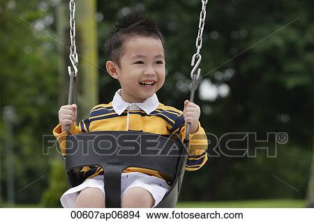 Young boy on playground swing, smiling, looking away View Large Photo Image Picture - Young boy on playground swing, smiling, looking away. Fotosearch
