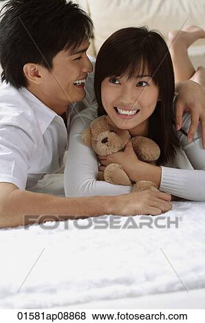 Young couple laughing while hugging and lying on the floor View Large Photo Image Stock Photo - Young couple laughing while hugging and lying on the floor. Fotosearch